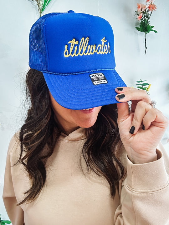 Royal blue foam trucker with “Stillwater” embroidered on it. 
