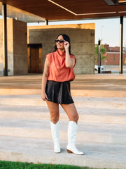 Woman wearing rust colored cap sleeve blouse 
