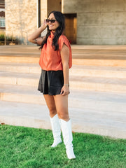 Woman wearing rust colored cap sleeve blouse 
