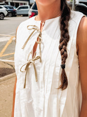 White sleeveless pleated mini dress with bow tie details.