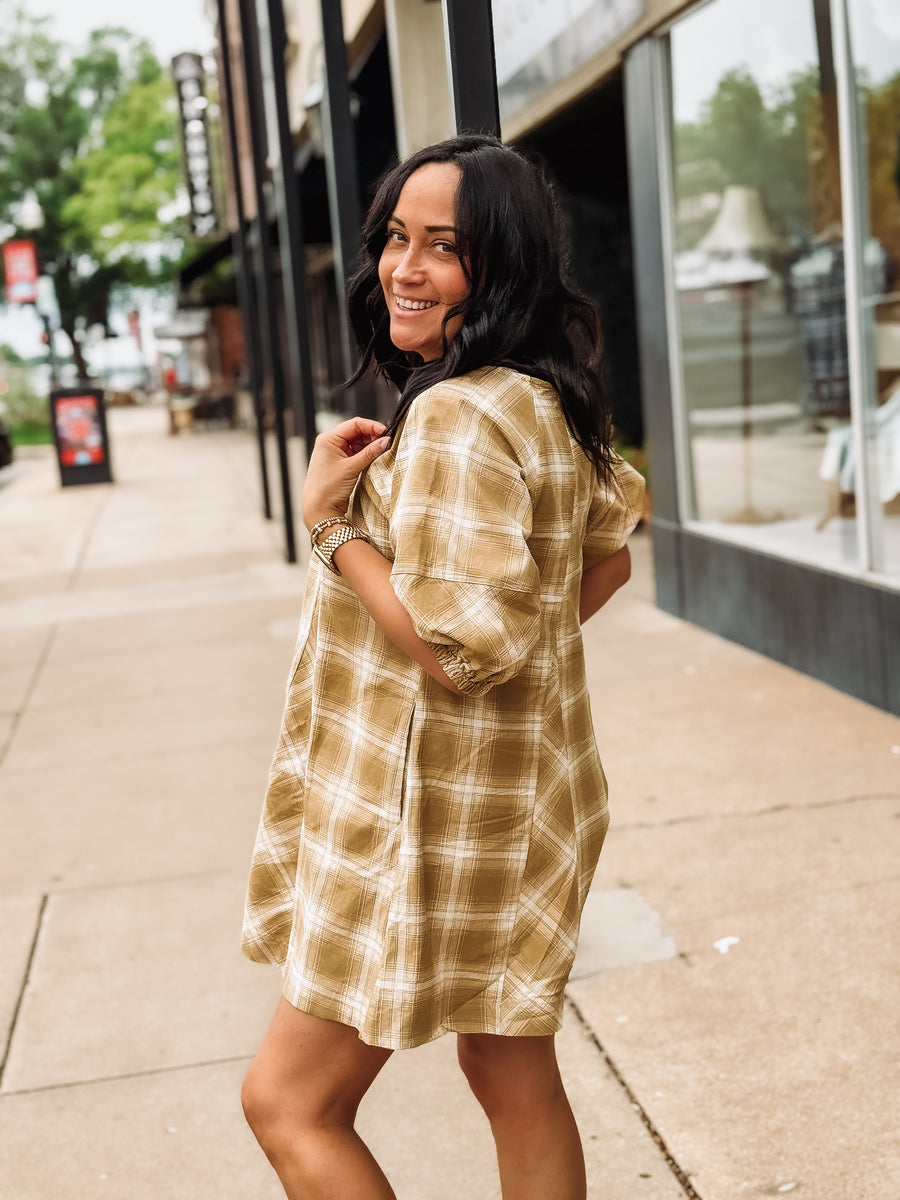 Woman wearing a plaid mustard colored romper on a city street
