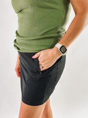 black skirt, hand in pocket, green ribbed tank