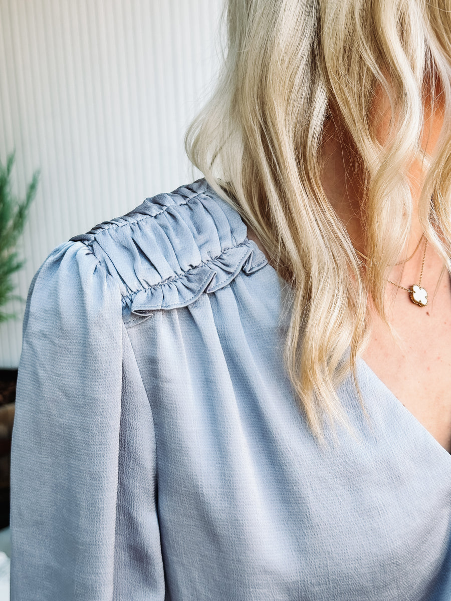 silver colored satin blouse with ruffle detail