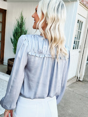 silver colored satin blouse with ruffle detail