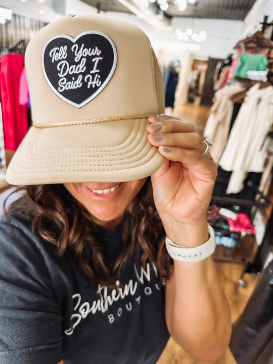 Black heart patch with "Tell Your Dad I Said Hi" typography on top of a khaki Otto hat.