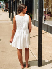 White sleeveless pleated mini dress with bow tie details.