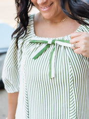 Woman wearing a green and white striped dress with a green ribbon detail.