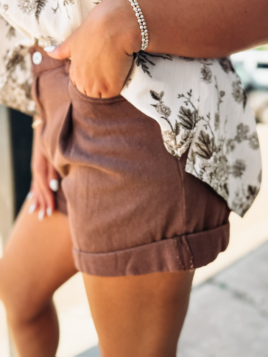 Light wash denim shorts with front pleats and a soft rolled hem, featuring a relaxed, casual fit